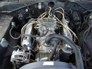 Engine compartment of 1973 Plymouth Scamp, with alternator clearly visible at left front  and the separate voltage regulator bolted to the side of the engine compartment.