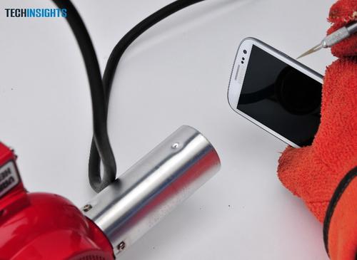 A UBM TechInsights lab tech applies an industrial-strength heat gun to soften the seal on the new Samsung Galaxy S3.