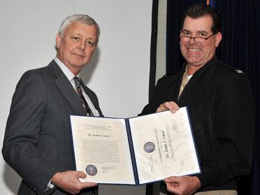 National Research Lab Commanding Officer Capt. Paul Stewart, right, presents the Navy Meritorious Civilian Service Award to Keith Lucas. He was honored for his team's 20 years of work to create ship models to advance anti-corrosion research. (Source: NRL)