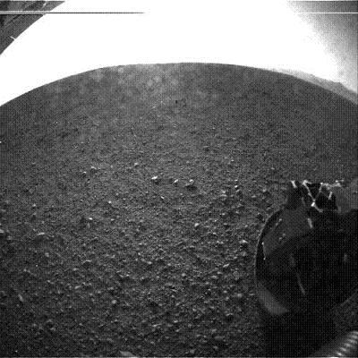 One of Curiosity's six wheels is shown in an early photo from the surface. The rim of Gale Crater is visible in the upper right.   (Source: JPL)