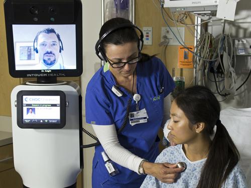 A nurse examines a patient under the watchful eye of a doctor via the RP-VITA, a robot co-developed by iRobot and InTouch Health that can autonomously travel around a hospital and allow a physician to administer care as if he or she is in the room with a patient.   (Source: InTouch Health)