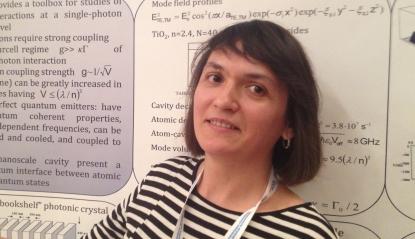 Elena Kuznetsova, an RQC scientist, stands before a poster paper outlining a new technique for transferring quantum information encoded on single photons to atoms, where they can be processed in a quantum computer.