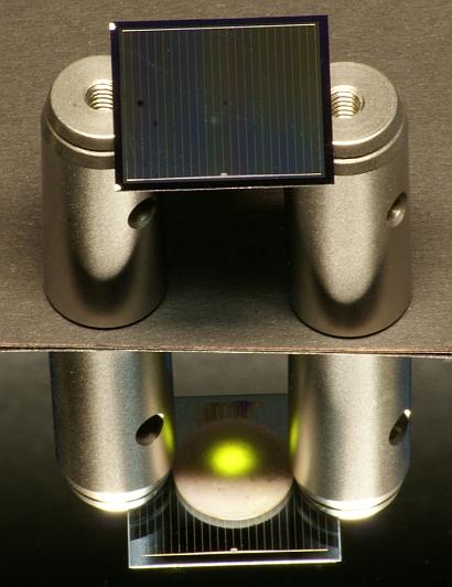 This two-sided (bi-facial) silicon solar cell -- positioned on aluminum cylinders -- is illuminated from above by an infrared laser.(Source: Fraunhofer ISE)