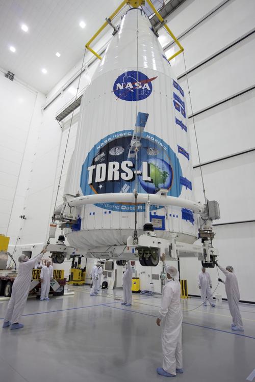Inside the Astrotech payload processing facility in Titusville, Fla., NASA's Tracking and Data Relay Satellite (TDRS-L) spacecraft has been encapsulated in its payload fairing. It is being lifted by crane for mounting on a transporter for its trip to Launch Complex 41 at Cape Canaveral Air Force Station. The TDRS-L satellite will be a part of the second of three next-generation spacecraft designed to ensure vital operational continuity for the NASA Space Network. TDRS-L is scheduled to launch from Cape Canaveral's Space Launch Complex 41 atop a United Launch Alliance Atlas V rocket at 9:05 p.m. EST on Jan. 23, 2014, the start of a 30-minute launch window.
The current Tracking and Data Relay Satellite system consists of eight in-orbit satellites distributed to provide near continuous information relay contact with orbiting spacecraft ranging from the International Space Station and Hubble Space Telescope to the array of scientific observatories. Click here for a larger image.
(Source: NASA/Kim Shiflett)