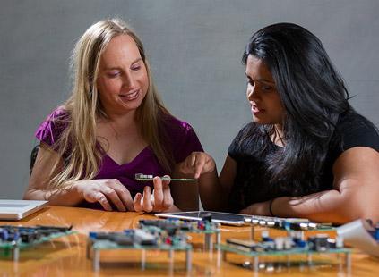 Professor Jennifer Hasler (left) and doctoral candidate Suma George examine a field-programmable gate array board. (Source: Rob Felt courtesy of Georgia Tech)