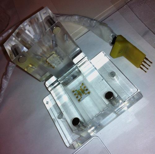 A flow cell the size of a wedding ring box accommodates a variety of printed microfluidic channels, sensors, and RF probes.