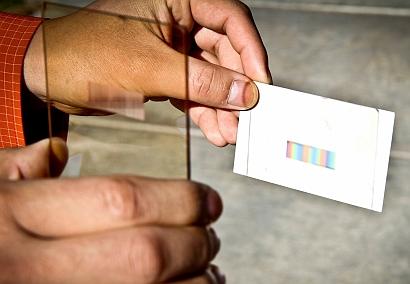 A thin rectangular plastic or glass layer -- or 'polychromat' -- developed by engineers at the University of Utah sorts sunlight into colors that can be absorbed by solar cells to increase their efficiency without increasing the cost. (Source: Dan Hixson, University of Utah)