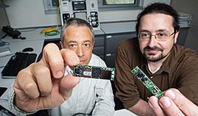 IPOS developers Luigi Gentile Polese (left) and Larry Brackney
show the essential parts of the IPOS --
the microprocessor and the camera. (Source: DOE Pulse; Photo credit: Dennis Schroeder)