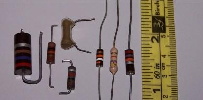 Some carbon resistors. The light colored one second from the left is a (rather battered) carbon film resistor -- a carbon track on a ceramic tube -- and the one in plastic probably is, too. The rest are carbon composition resistors -- basically just a rod of carbon inside a tube. Most of them have silver tolerance bands, which mark them as 10% types.(Click here to see a larger image.)