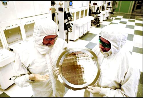 Michael Liehr of the SUNY College of Nanoscale Science and Engineering, left, and Bala Haranand of IBM examine a wafer comprised of the new SiGe 7nm-based integrated circuits.  (Source/Credit: Darryl Bautista/IBM)